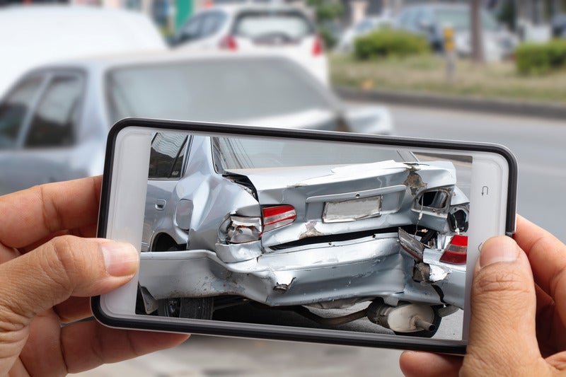 man taking picture of damaged car